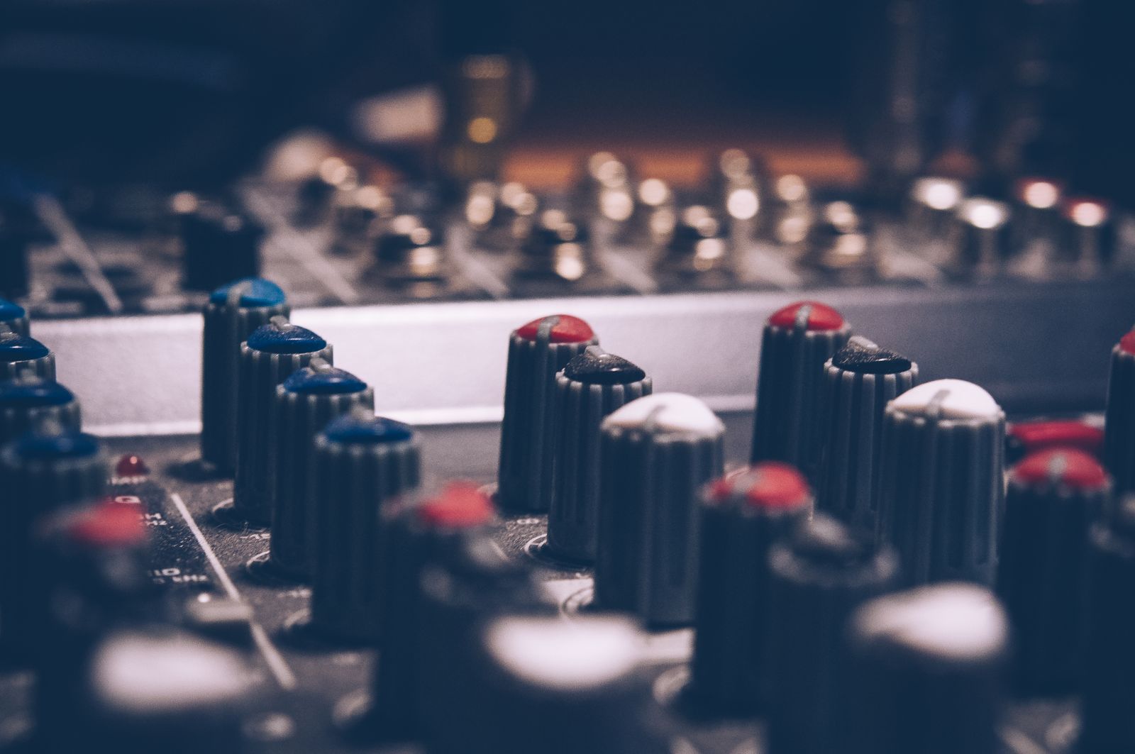 Close-up of audio equalizer knobs and levels in a dim studio