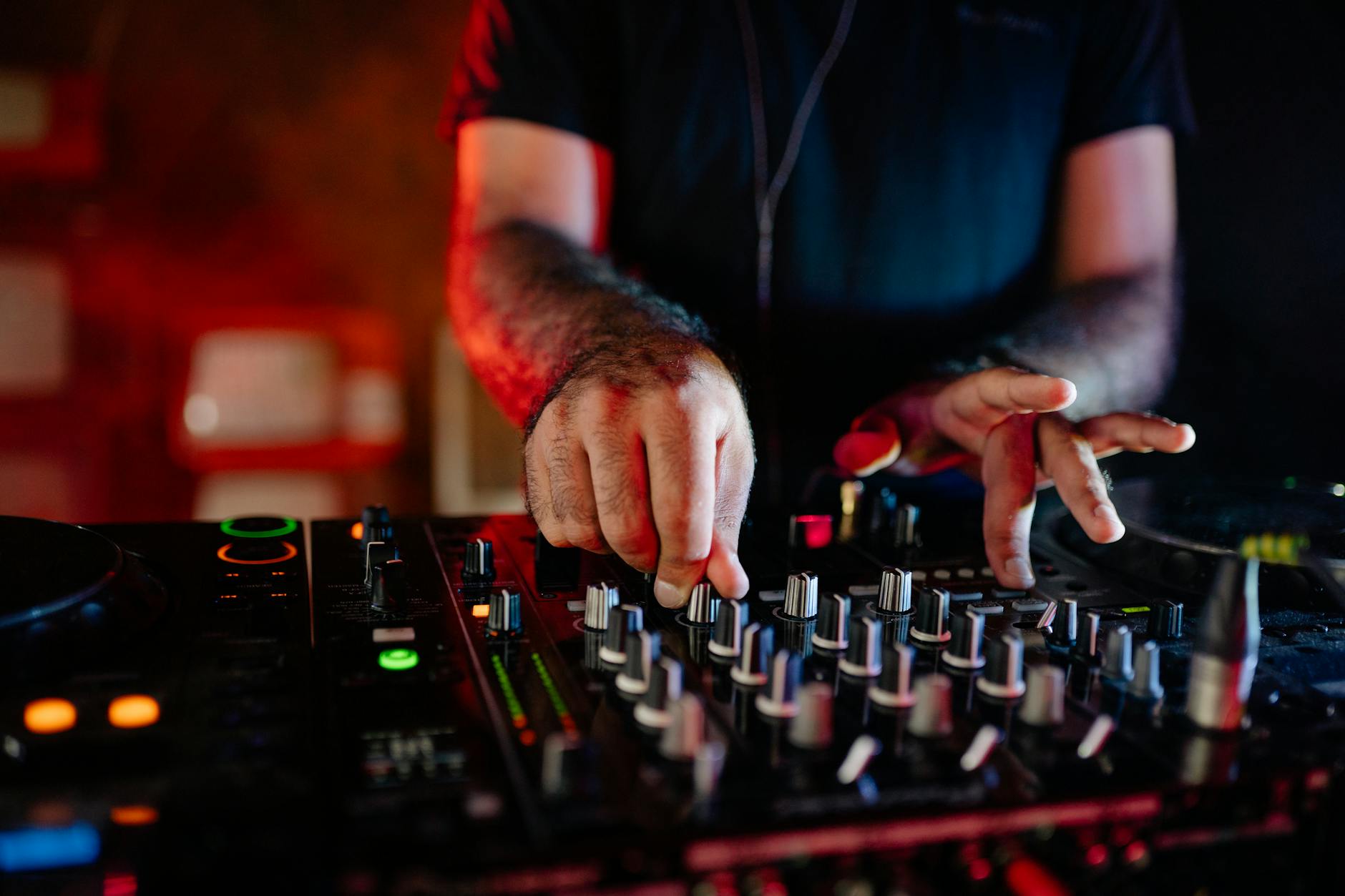 DJ at the mixer beat matching two tracks under low club lights